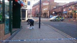 A forensics officer photographs evidence from the stabbing scene in Hanley