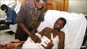 Injured miner Vincent Chenjela is cared for by his father in hospital in Lusaka, Zambia (18 Oct 2010)