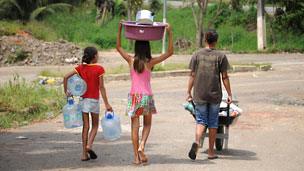 Children collect fresh water at their temporary housing camp