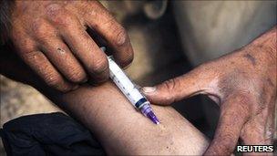File image of a heroin addict injecting a fellow addict in Kabul, Afghanistan