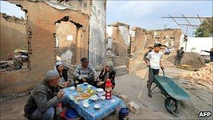 Ethnic Uzbeks eat outside their destroyed house on 7 October 2010