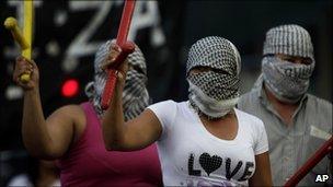 Masked demonstrators brandish batons during the protest in Buenos Aires