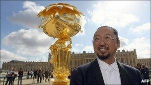 Takashi Murakami in front of Oval Buddha Gold in the Versailles courtyard