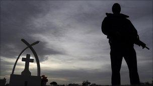 A soldier stands guard at the funeral of victims of a shooting in Ciudad Juarez