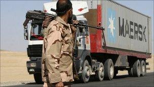 A private security contractor watches a Nato supply truck drive past in the province of Ghazni, south-west of Kabul, Afghanistan, Wednesday, Oct 27, 2010.