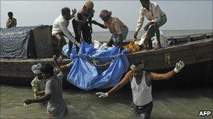 Fishermen carry a recovered body from the waters near Kakdwip, some 100km south of Calcutta, on 2 November, 2010, following the sinking of a ferry on 30 October.