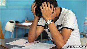 A child with his head in his hands studying an exam paper.
