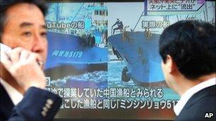 A man watches TV news comparing the YouTube footage with an image of the Chinese boat involved in the collision on 5 November 2010