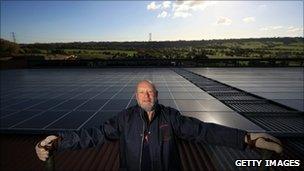 Michael Eavis stands in front of his solar panels