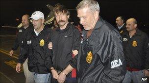 Viktor Bout (centre) arrives in New York, escorted by US federal agent (16 November 2010)