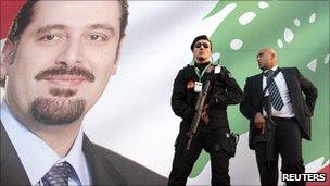 Turkish and Lebanese security men stand in front of a poster of Lebanon's Prime Minister Saad Hariri