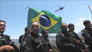 Brazilian police plant a flag in the Complexo do Alemao slum in Rio de Janeiro on Sunday
