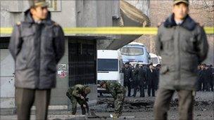 Policemen stand guard as security personnel work on site of a blast in Bishkek