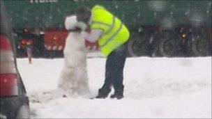 Driver building snowman at side of road in Coatbridge, North Lanarkshire, Scotland
