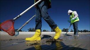 Workers clean tarballs from the BP oil spill on Waveland beach, Mississippi on 6 December 2010