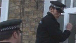 Police officers knock on the door of a house during the operation