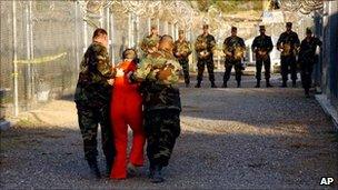 A prisoner walking with US soldiers at Guantanamo Bay prison