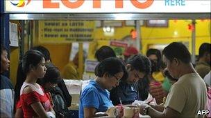 People fill out their lottery cards at a lottery outlet in Manila on 29 November 2010