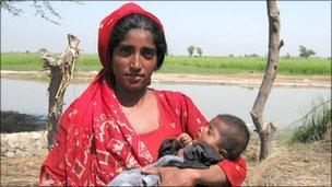 Woman with her baby surrounded by flood waters, Sindh province