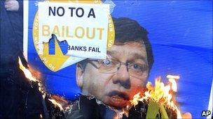 Anti-bail-out protesters burn a placard with the face of Taoiseach Brian Cowen on it
