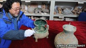 A Shaanxi Provincial Archeological Institute official displays the bronze vessel thought to contain the ancient soup