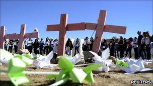 People stand near wooden crosses in a field near Ciudad Juarez where the bodies of eight murdered women were found in November 2010