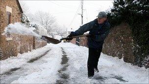 A man clears snow and ice from the road