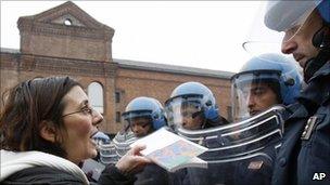 Researchers and students offer books to police officers during a protest in Milan, 22 December 2010