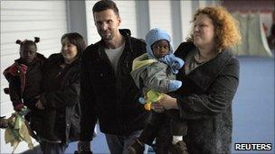 French adoptive families hold newly-adopted children upon arrival in Paris on 22 December 2010