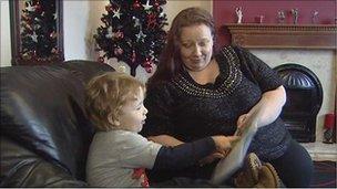 Mother and son reading story book in front of Christmas tree