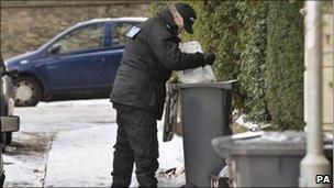 Police officer searching through bins