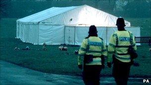 Police officers walk by a tent set up to exhume the remains of James Hanratty at Carpenders Park cemetery in Bushey, Hertfordshire
