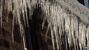 Icicles hang down from a gutter