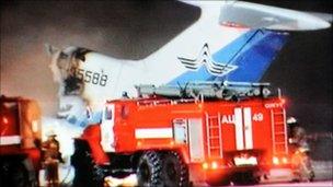 A grab taken on January 1, 2011 from the Russian NTV channel shows firefighters standing in front of the wreckage of the Russian passenger Tu-154 aircraft after it burst into flames
