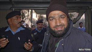 A man identified as Malik Mumtaz Hussein Qadri is driven away by police after the killing