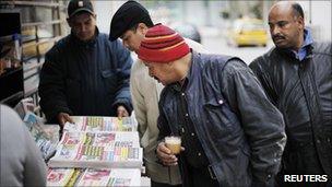 Men look at newspapers at a street kiosk in downtown Tunis, January 19, 2011