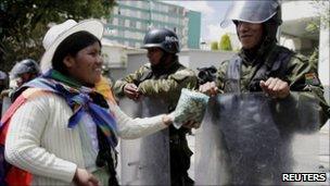 Indigenous woman offering coca leaf to riot police in La Paz