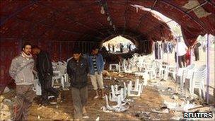 Residents inspect the site of a bomb attack inside a funeral tent in Baghdad. Photo: 27 January 2011
