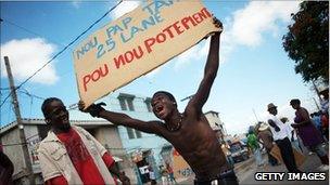 Protester holds sign saying, "We won"t wait 25 years to file a complaint", Port-au-Prince, 23 January 2011
