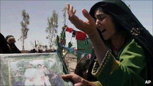 An Afghan woman mourns as she holds a poster with photos of her family members killed during a US-led raid in Herat province in Afghanistan in 2008