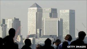 Workers silhouetted in front of the Canary Wharf skyline, London
