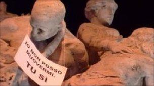 A banner on a statue in Rome which reads: "I can't go anywhere, you can"