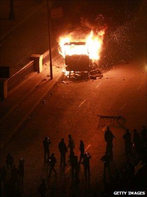 Protesters use their mobile phones to photograph a burning police vehicle during clashes in Cairo on 28 January 2011