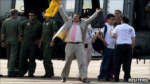 Hostage Armando Acuna raising his arms in triumph in front of the Brazilian helicopter that brought him out of the jungle