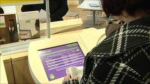 A woman looking at a database of job vacancies at a Job Centre Plus
