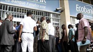 People wait in line on 16 February 2011 in front of a branch of the pan-African bank Ecobank in Abidjan