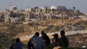 Palestinian teenagers sit opposite the Jewish settlement of Modiin in the West bank, 18 February