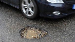 A car drives past a pothole in a suburban street in London