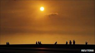 People sit along Havana's seafront boulevard, El Malecon, during sunset
