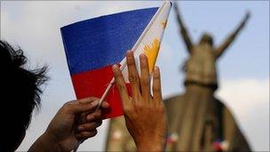 A student waves a miniature Philippine flag during a re-enactment of the 1986 People Power revolt at the People Power Monument in suburban Manila on 24 February 2010